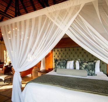 Elegant canopy bed in a spacious suite at Arathusa Safari Lodge with luxurious decor.