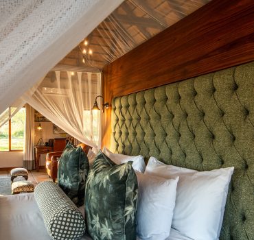 Elegant canopy bed with tufted headboard and luxurious pillows at Arathusa Safari Lodge.