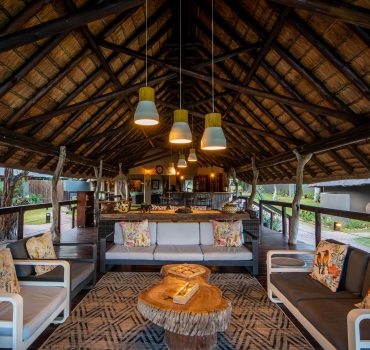 Outdoor lounge area under a thatched roof at Arathusa Safari Lodge with comfortable seating and rustic decor.