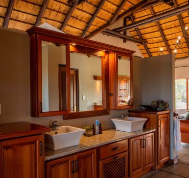 Luxurious bathroom with double sinks and elegant wood cabinetry at Arathusa Safari Lodge.