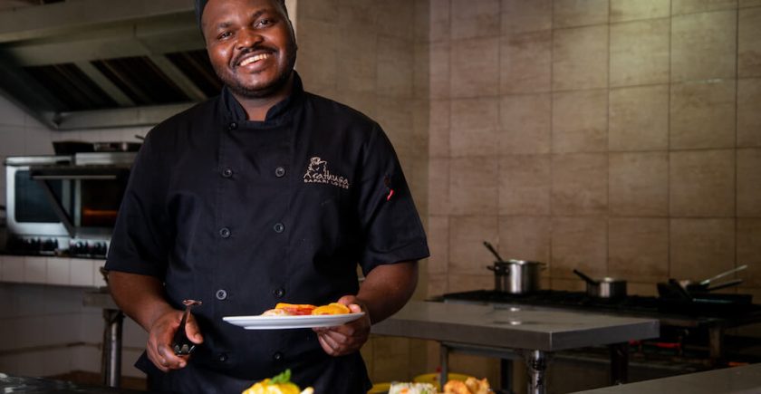 sous-chef-holding-a-plate-of-food-and-smiling-at-the-camera