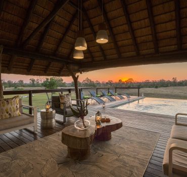 Outdoor lounge and pool area at Arathusa Safari Lodge with sunset view and comfortable seating.