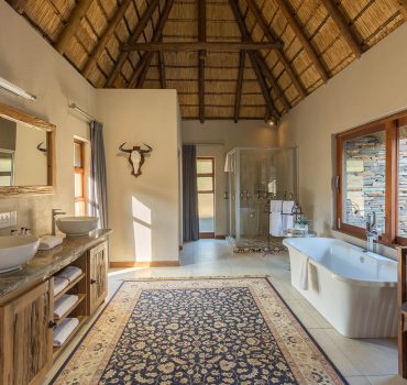 Spacious and elegant bathroom with double sinks and a bathtub at Arathusa Safari Lodge.