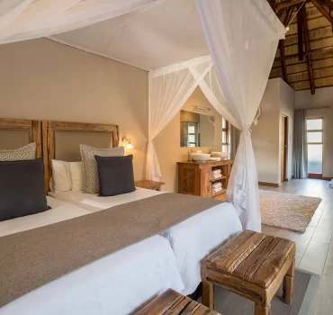 Luxurious interior of a water-facing suite at Arathusa Safari Lodge with comfortable bedding and elegant bathroom.