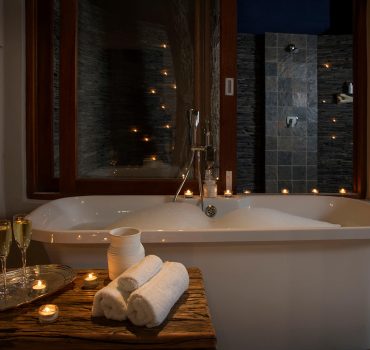 Elegant and luxurious bathtub setup with candles and champagne at Arathusa Safari Lodge.