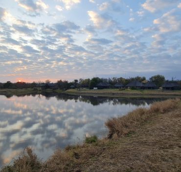 thatch-roof-houses-by-a-dam-and-clouds-reflecting-on-dam-water