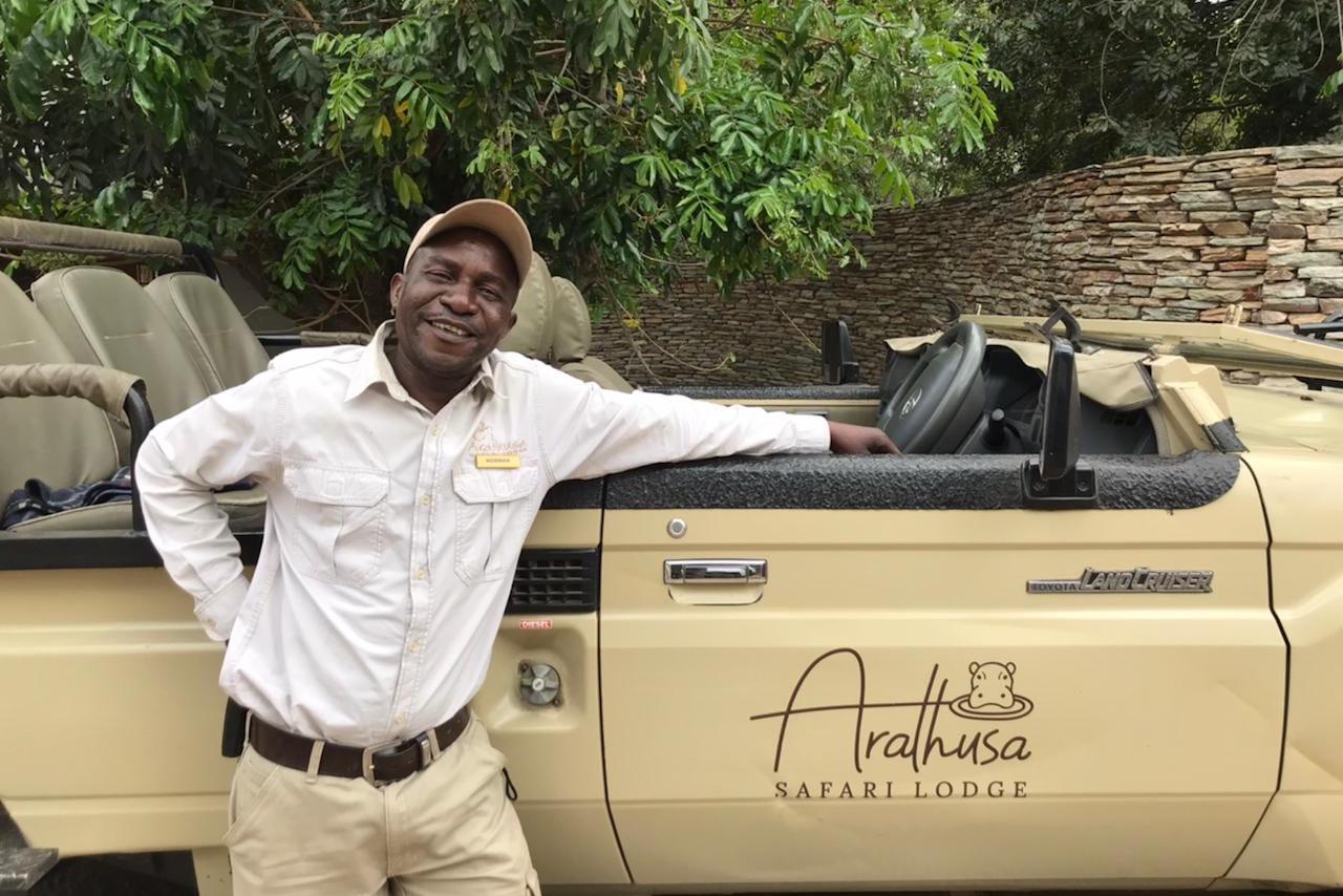 black-man-standing-next-to-a-brown-safari-vehicle