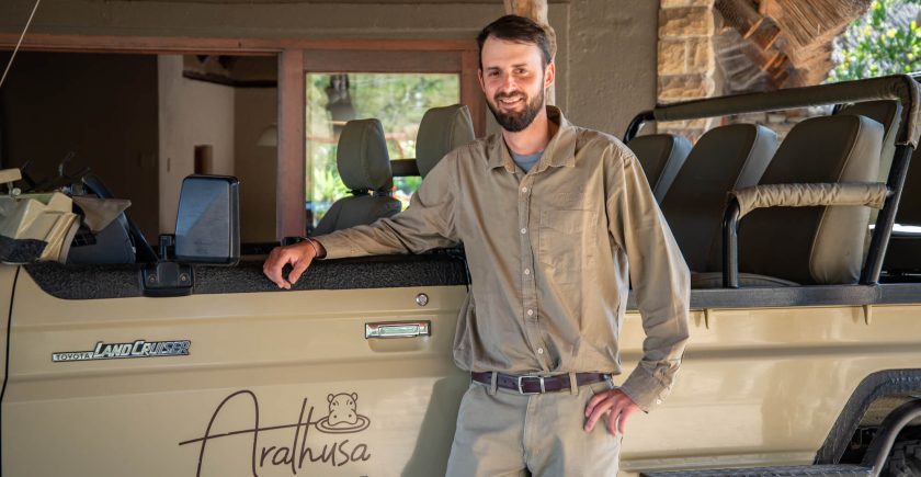 white-man-standing-next-to-a-brown-safari-vehicle