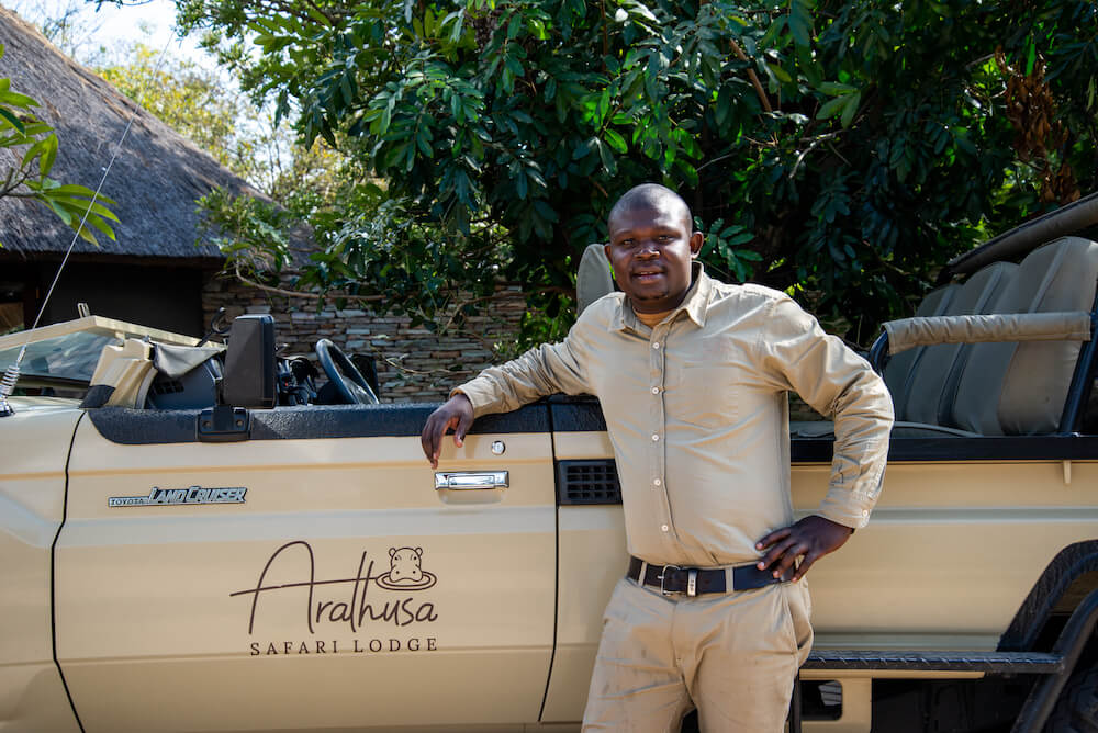 black-man-standing-next-to-a-brown-safari-vehicle