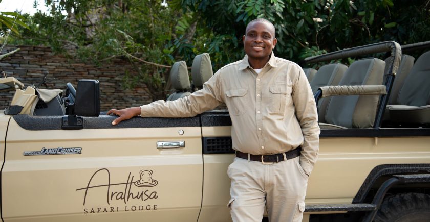 black-man-standing-next-to-a-brown-safari-vehicle