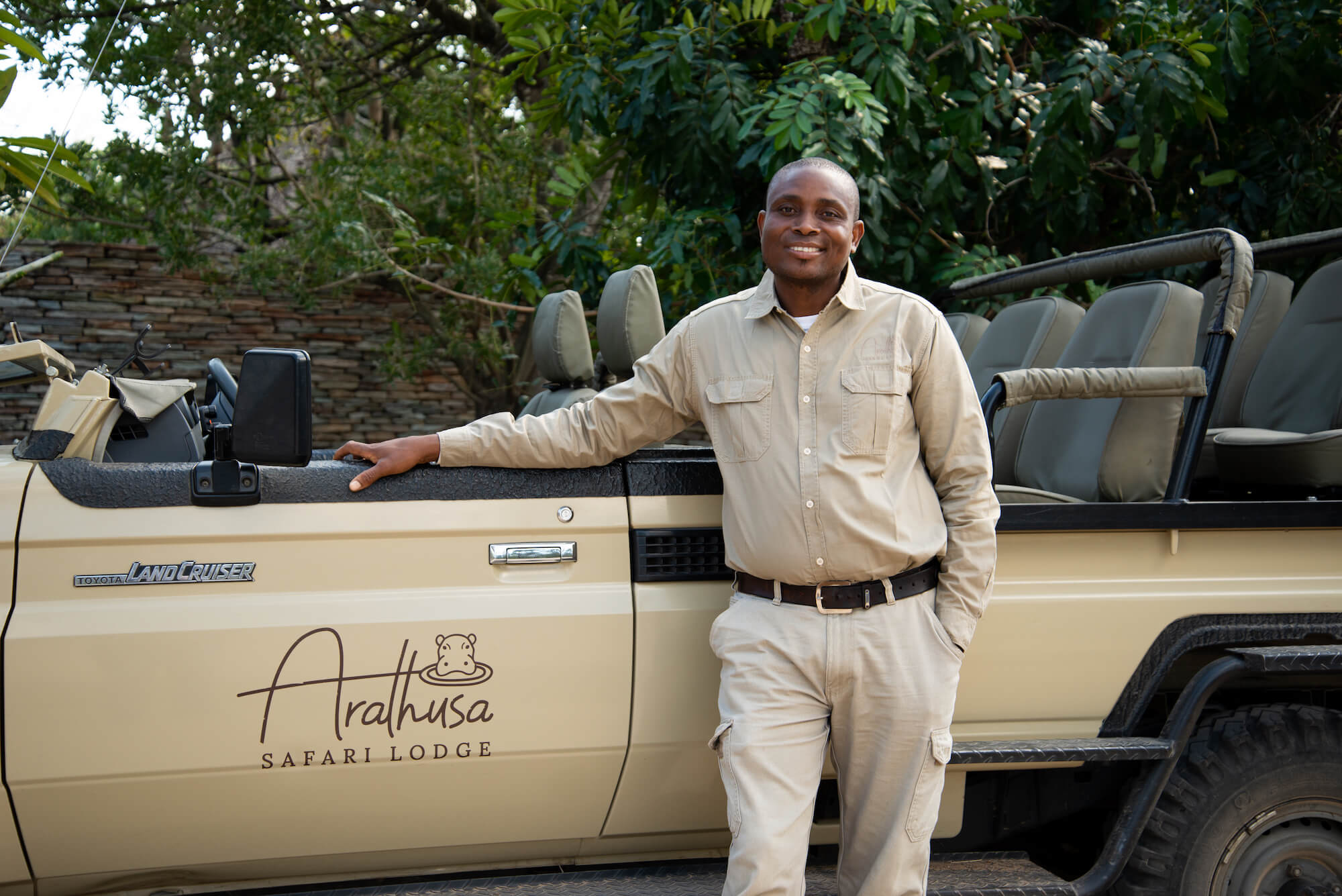 black-man-standing-next-to-a-brown-safari-vehicle