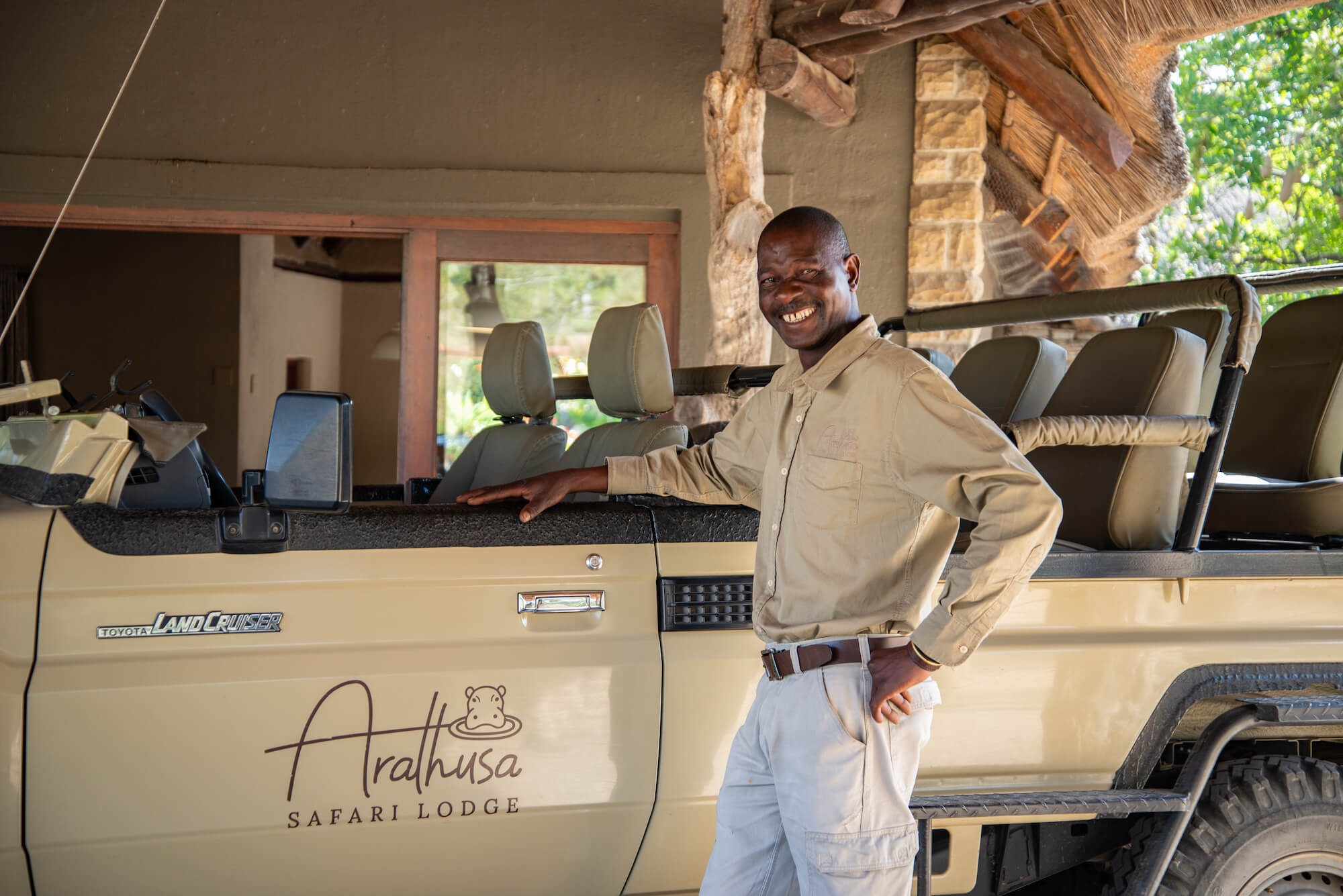 black-man-standing-next-to-a-brown-safari-vehicle